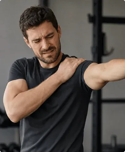 An athlete holds his shoulder while raising his arm in a gym, illustrating discomfort that may affect shoulder impingement recovery time