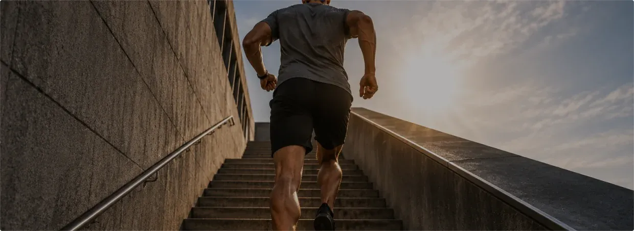 Low-angle view of a man sprinting up concrete outdoor stairs.