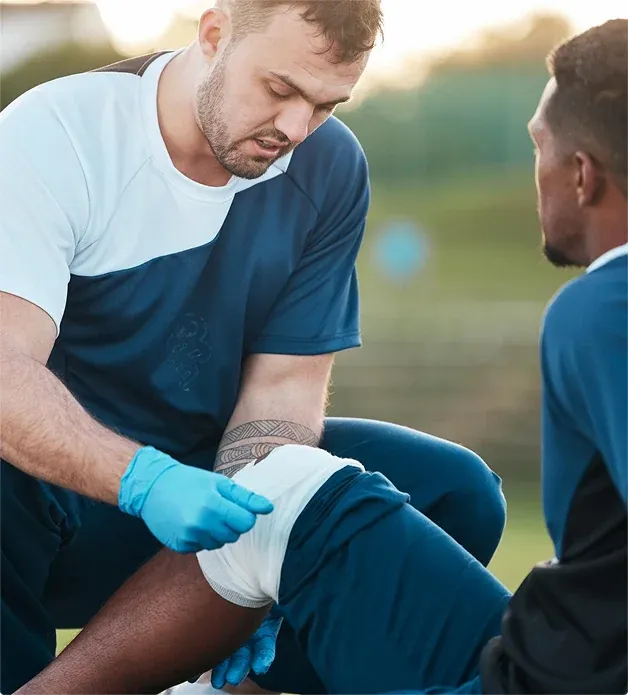 Trainer securing a compression bandage around an athlete's knee.