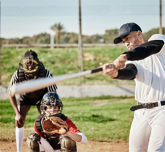 Batter swinging a baseball bat with a catcher crouching behind home plate.