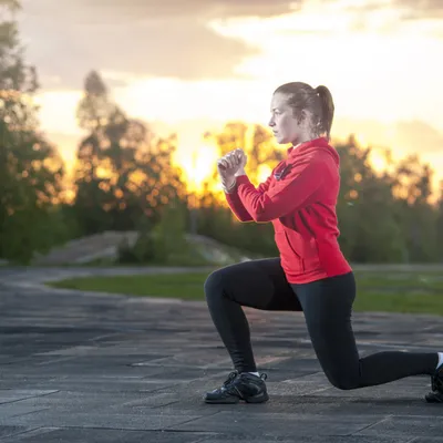 Woman holds lunge at sunset outdoors; functional movement training improves balance, hip strength, and mechanics