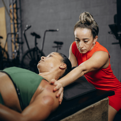 A therapist supports a patient's shoulder during hands-on sports rehabilitation treatment on a therapy table