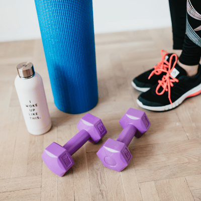 Dumbbells, shoes, a water bottle, and an exercise mat are arranged for sports rehabilitation training