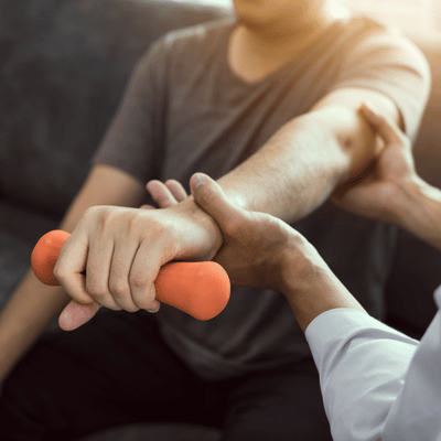 Therapist supports a person's forearm while they hold a dumbbell during physical therapy