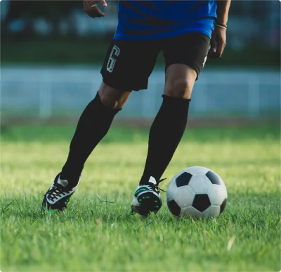 Soccer player dribbling a ball on a field during soccer injury rehab and cutting mechanics training.