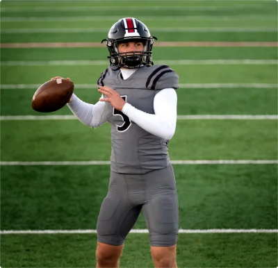 Football player holding a football on a field during football injury rehab and speed training.