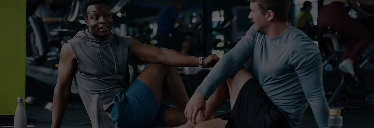 Two athletes resting together on the floor of a gym.